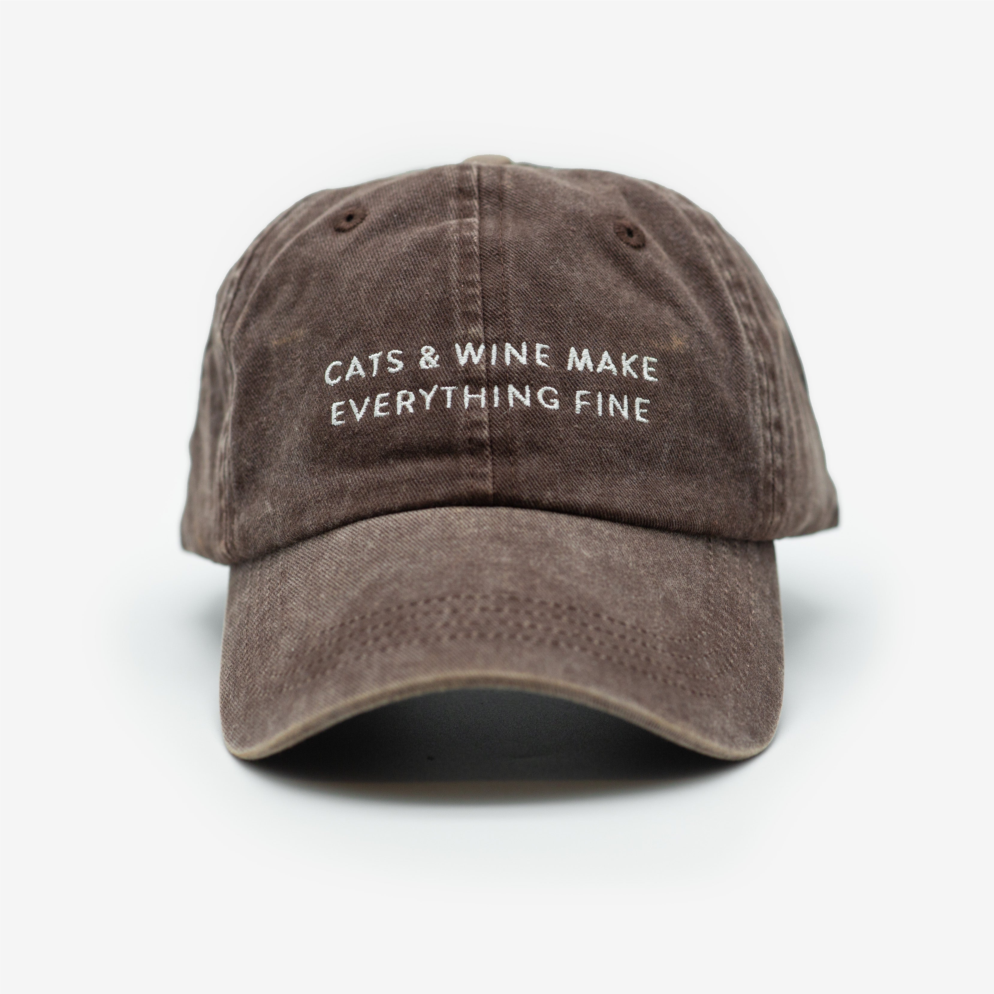 A brown denim cap with the text 'CATS & WINE MAKE EVERYTHING FINE' embroidered on the front.