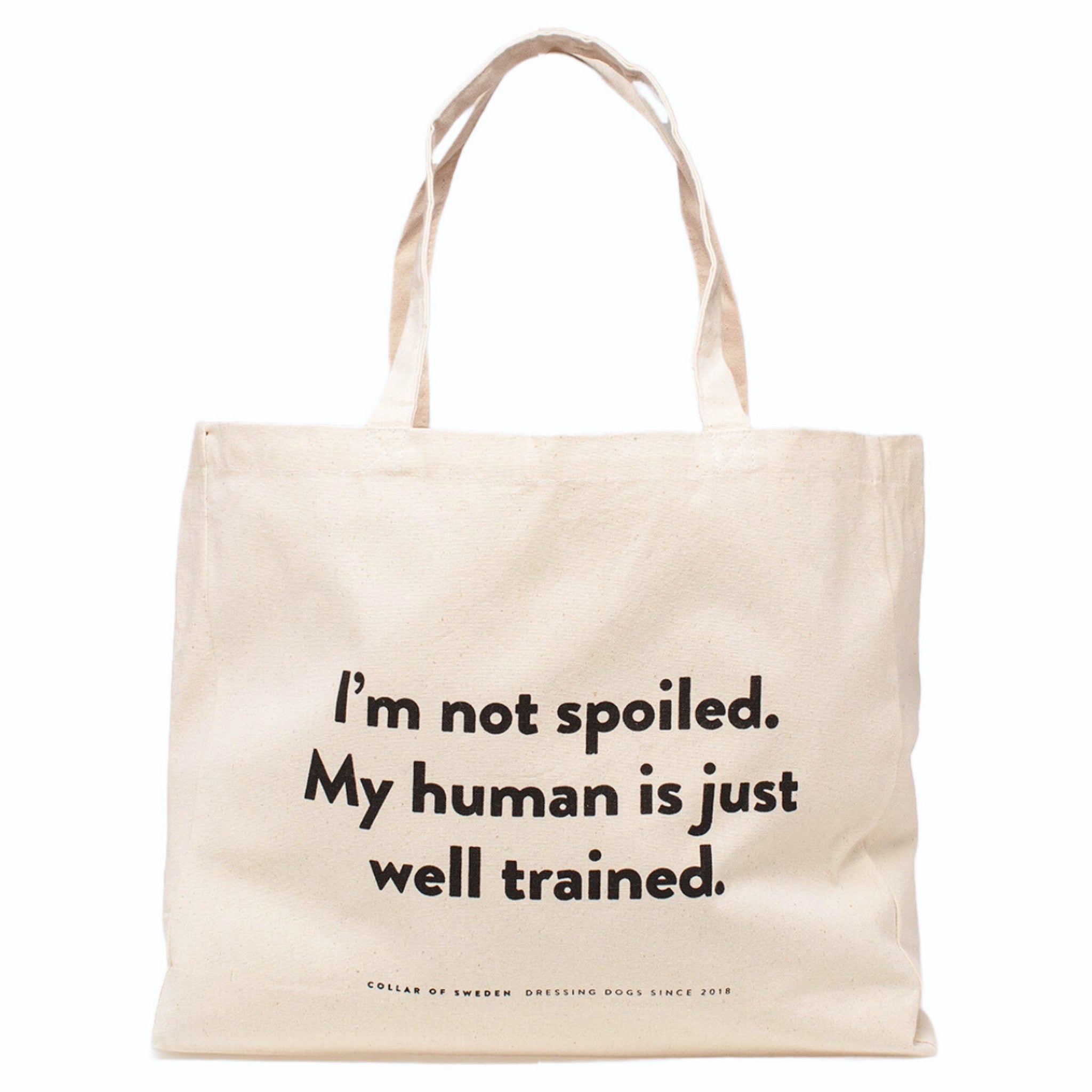 Beige tote bag with the humorous text "I'm not spoiled. My human is just well trained. on a white background